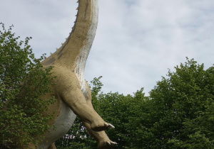 Dzieci stoją na tle figury dinozaura