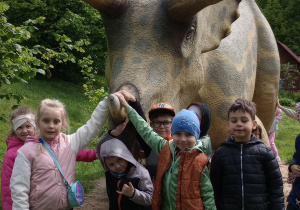 Kikoro dzieci stoi przy figurze dinozaura