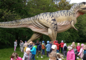 Dzieci stoją przed figurą dinozaura