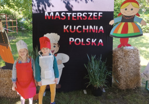 Dwie dziewczynki stoja przy banerze z napisem Masterszef