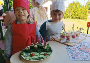 Dwie dziewczynki siedzą przy stoliku z wykonanymi potrawami