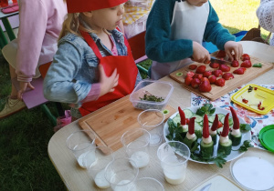 Dwie dziewczynki siedzą przy stoliku i przygotowują potrawy