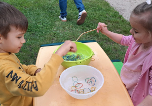 Dwoje dzieci łowi gumki z miski z wdą