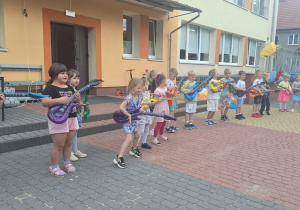 Dzieci z grupy Świetliki stoją w szeregu z gitarami