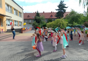 Prowadząca i dzieci podnoszą chusty w górę