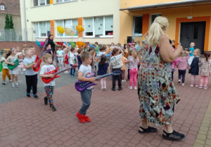 dzieci idą z gitarami w rzędzie