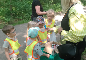 Prowadząca podaje dzieciom do wąchania zapach w pojemniku