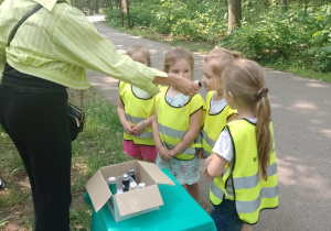 Prowadząca podaje dzieciom do wąchania zapach w pojemniku
