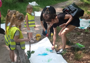 Drużyna z nauczycielką malują obraz pezlem z materiałów przyrodniczych