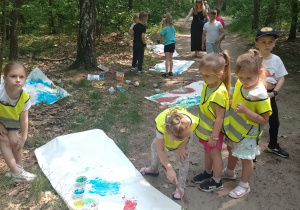 Kikoro dzieci maluje obraz pędzlem zrobionym z materiałów przyrodniczych