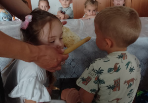Pani pokazuje dzieciom plaster wosku i świecę
