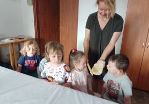 Pani pokazuje dzieciom plaster wosku i świecę