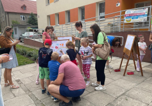 Rodzice z dziećmi podczas tworzenia obrazu wiosennej łąki na sztalugach