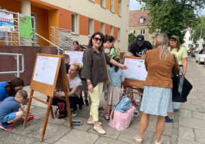 Rodzice z dziećmi podczas tworzenia obrazu wiosennej łąki na sztalugach