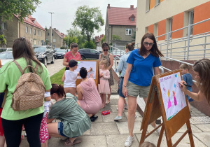 Rodzice z dziećmi podczas tworzenia obrazu wiosennej łąki na sztalugach