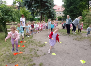 Dzieci z trzech grup ustawione w rzędach podczas pokonywania konkurencji sportowych