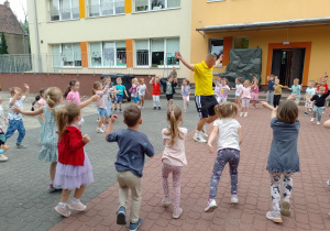 Dzieci stoją w kole podczas rozgrzewki prowadzonej przez trenera