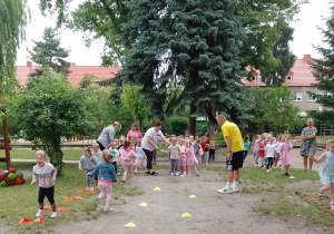 Dzieci z trzech grup ustawione w rzędach podczas pokonywania konkurencji sportowych