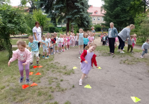 Dzieci z trzech grup ustawione w rzędach podczas pokonywania konkurencji sportowych
