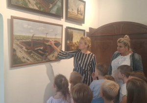 Pani kustosz pokazuje dzieciom obraz z fabrykami miasta