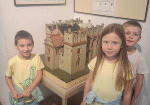 Troje dzieci stoi przy makiecie zamku
