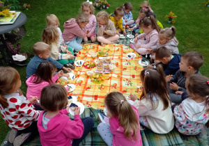 Dzieci siedzą na kocach w trakcie poczęstunku