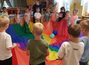 Dzieci chodzą z chustą, na której leżą balony
