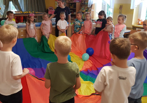 Dzieci trzymają chustę animacyjną, na której leżą balony