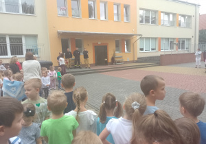 Trzech strażaków stoi przed dziećmi
