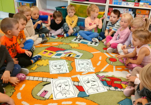 Dzieci siedzą w kręgu, w środku którego leżą obrazki z emocjami