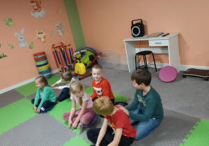 Dzieci w parach siedzą jedno za drugim i robią masażyk na plecach