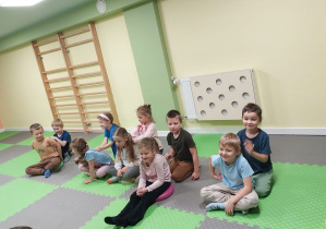 Dzieci w parach siedzą jedno za drugim i robią masażyk na plecach