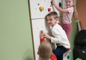 Troje dzieci wspina się po ściance