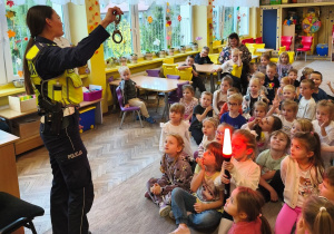 Pani policjantka pokazuje dzieciom kajdanki