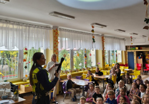 Pani policjantka pokazuje dzieciom światlo z latarki na suficie