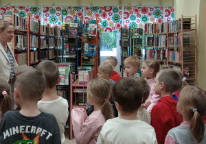 Pani bibliotekarka pokazuje dzieciom kartę biblioteczną