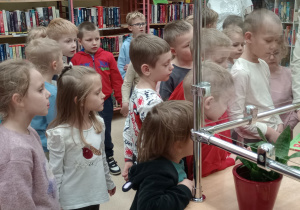 Pani bibliotekarka pokazuje dzieciom, jak wypożycza się książkę