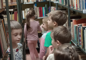 Dzieci chodza między regałami z książkami