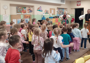 Para tancerzy chwyta się pod boki, a dzieci stoją i naśladują