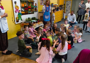 Dzieci siedzą na dywanie i trzymają słoiki z kapustą