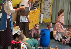 Panie pokazują dzieciom naczynia i narzędzia do kiszenia kapusty