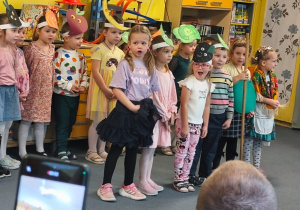 Dzieci w przepaskach z warzywami stoją podczas inscenizacji