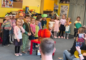 Dzieci w przepaskach z warzywami stoją podczas inscenizacji