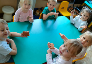 Kilkoro dzieci z grupy Motylki siedza przy stole i jedzą pierniczki