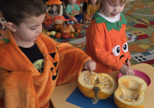 Dwoje dzieci dotyka przekrojonej dyni