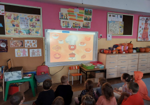 Dzieci oglądają film edukacyjny na tablicy multimedialnej