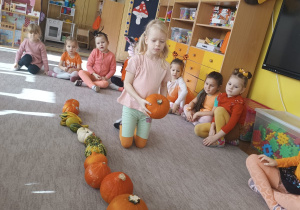 dziewczynka układa dynie w szeregu