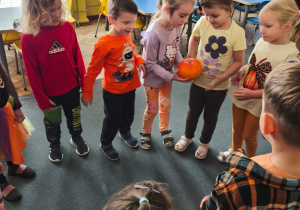 Dzieci podają sobie dynię w kole