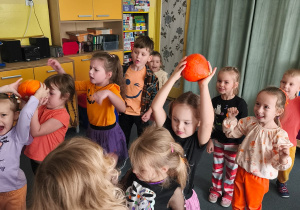 Dzieci podają górą w dwóch rzędach dynie