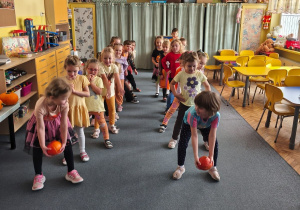 Dzieci podają dynie w dwóch rzędach dynie dołem między nogami